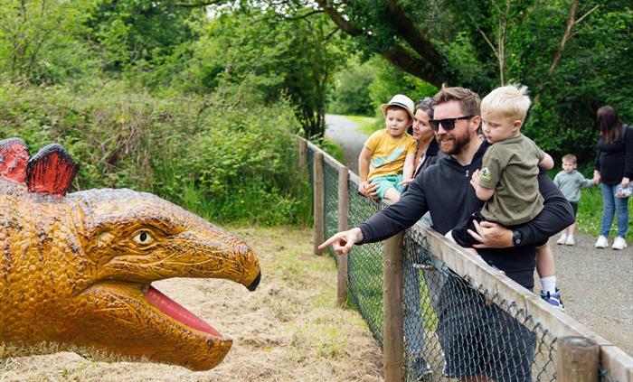 A Father and son and mother and son looking at the Stegosaurus display.